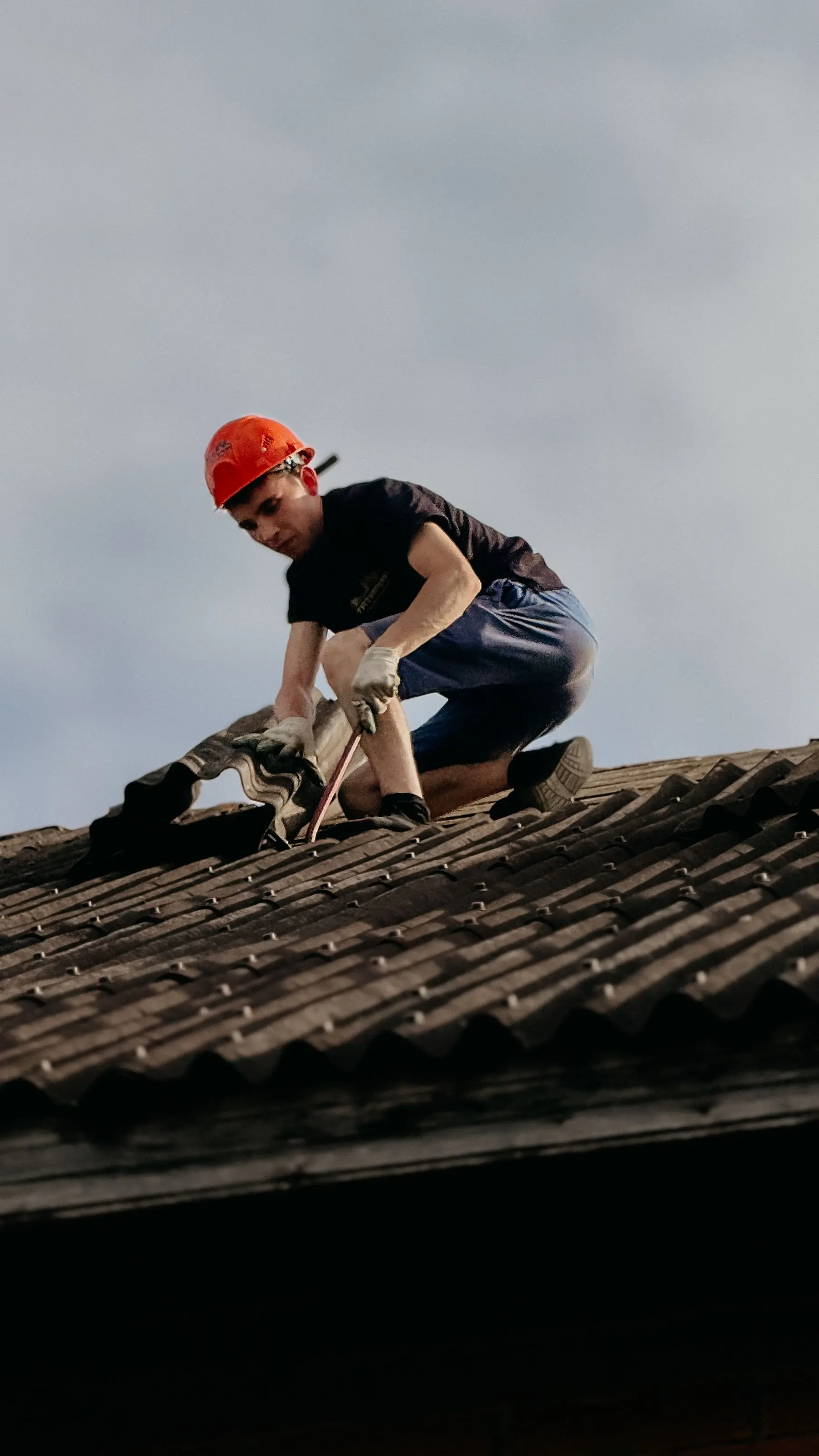 Couvreur avec casque de sécurité posant une tuile sur toiture