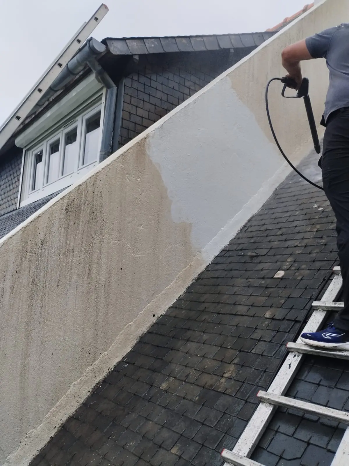 Artisan RENOV TOITURE 22 en train de nettoyer une façade au jet à Saint-Brieuc